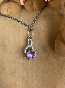 Hand pendant holding a faceted amethyst. Sterling silver handmade stone set pendant.