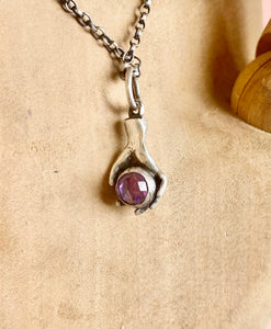 Hand pendant holding a faceted amethyst. Sterling silver handmade stone set pendant.